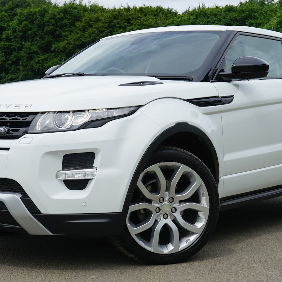 White luxury SUV parked on the roadside in a close exterior view with green landscape behind