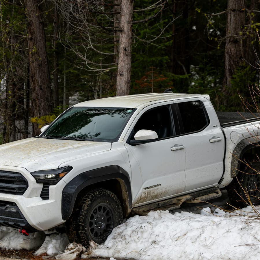 White pickup truck in snow near trees in a close front exterior view