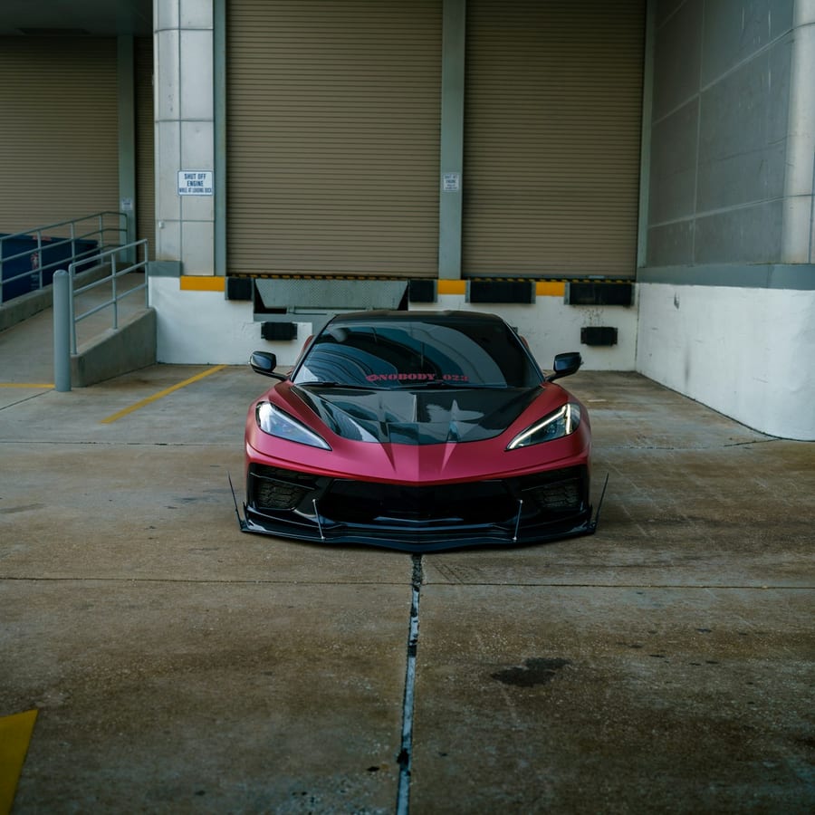 Red modern sports car parked in a lot, shown in a close front-three-quarter exterior view