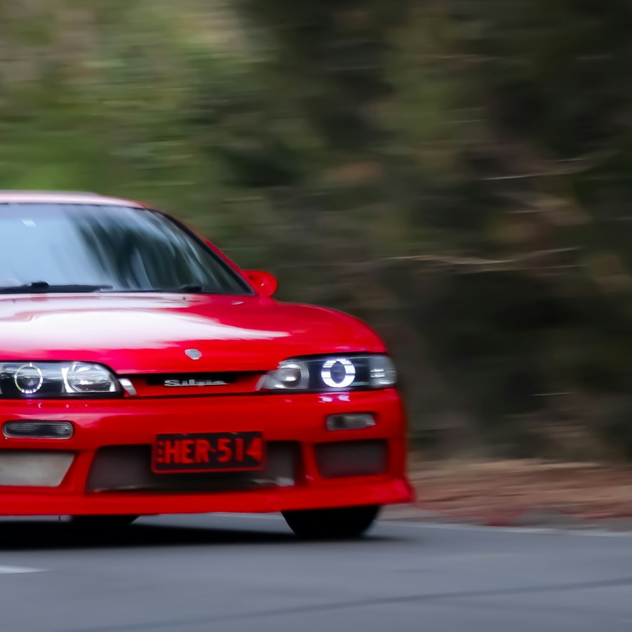 Red coupe sports car on the road in daylight, shown in a tight front exterior close-up