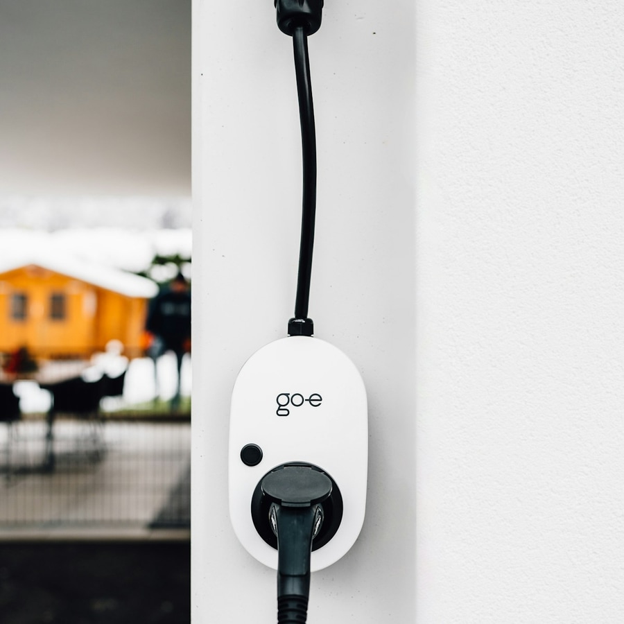 Wall-mounted EV charger plugged in with cable in a tight product-style close-up