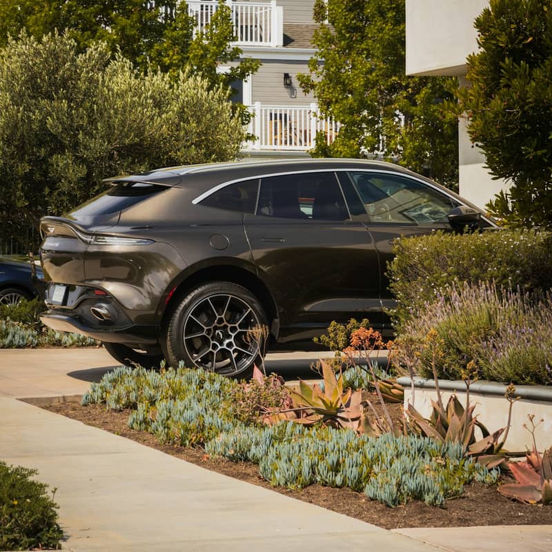 Dark luxury SUV parked near modern buildings in a close front-three-quarter exterior view