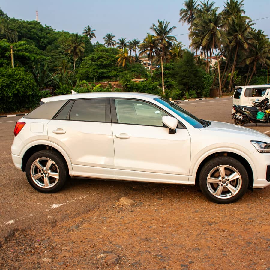 White SUV parked near trees in a tight front exterior close-up