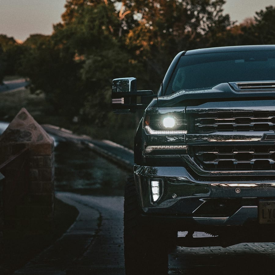Front close-up of a pickup truck on a road at sunset with warm light on the grille