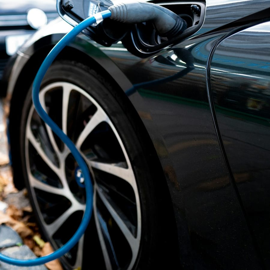 Plug-in electric vehicle at a charging cable in a tight close-up of the port and connector