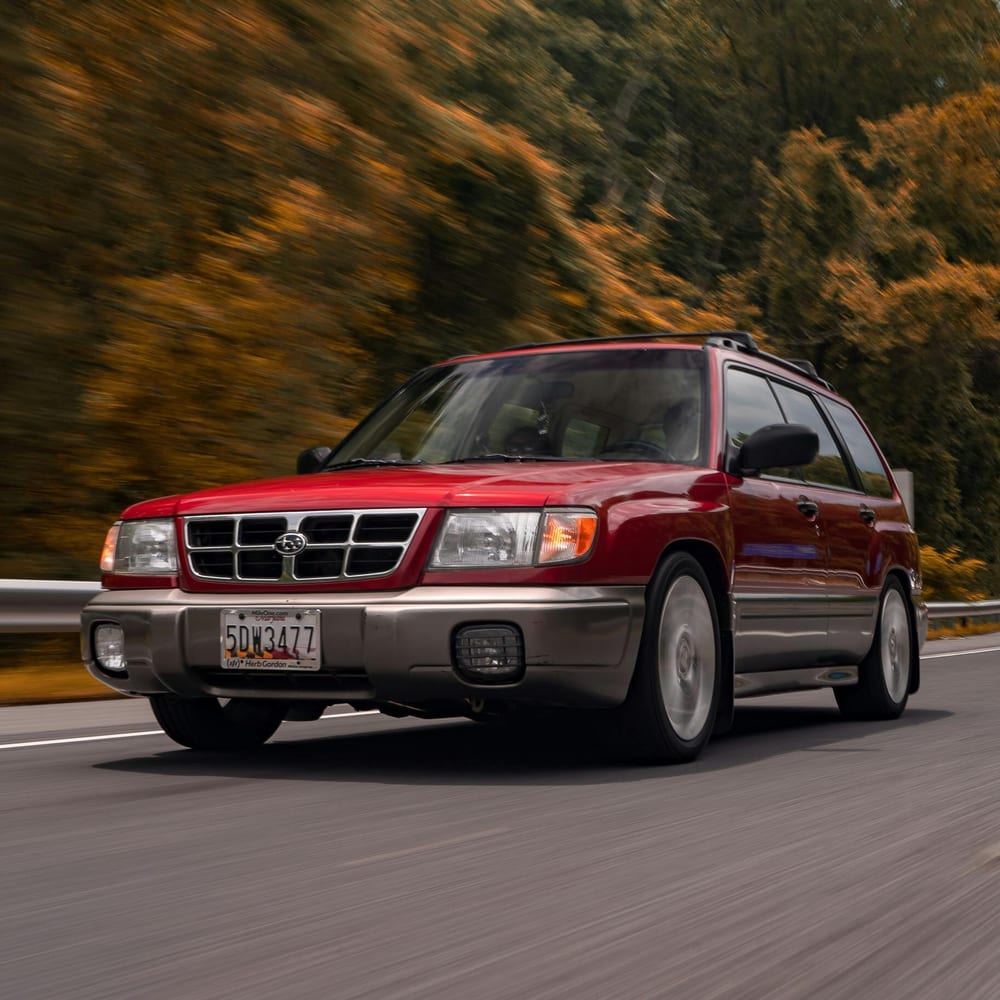 Red SUV on a road in autumn shown in a close front exterior view